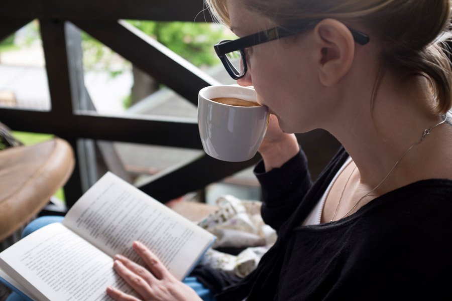 コーヒーを飲みながら本を読む女性